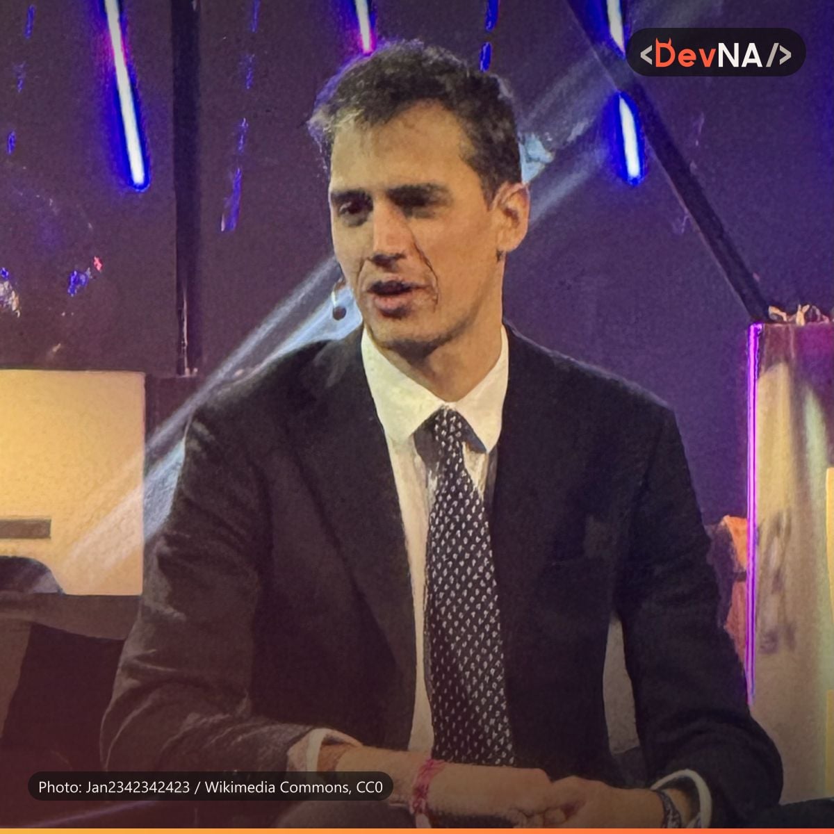 آرتور منش، هم‌بنیان‌گذار و مدیرعامل Mistral AI، با کت تیره و کراوات و میکروفون کوچک کنار صورت، نشسته و در حال صحبت زیر نور بنفش صحنه در رویداد Techarena 2026